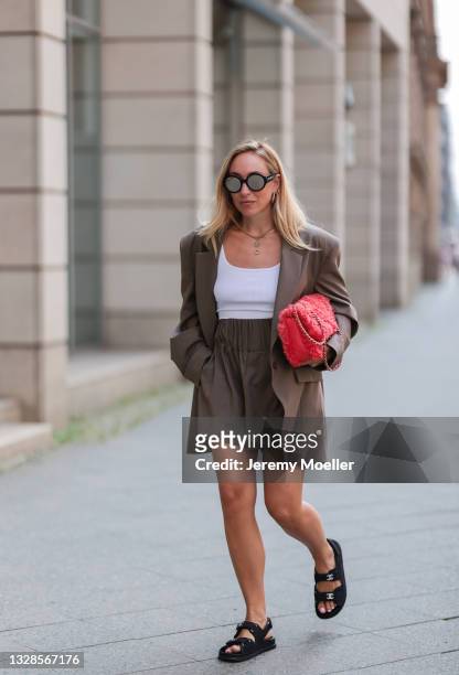 Sonia Lyson wearing orange Chanel bag, brown by Aylin Koenig two piece, black Chanel shades and black sandals on July 12, 2021 in Berlin, Germany.