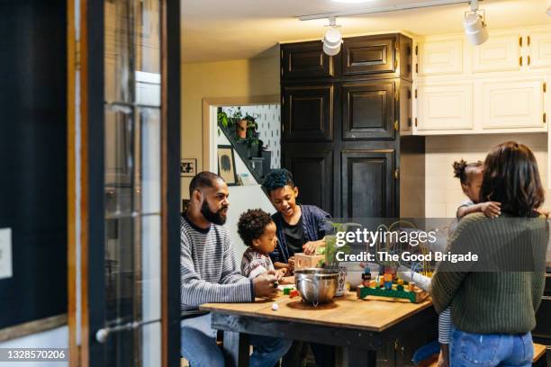 family having fun in kitchen at home - mittelstand stock-fotos und bilder