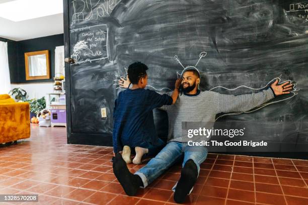 father and daughter drawing on chalkboard at home - ludoteca foto e immagini stock