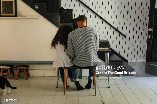 rear view of father and daughter playing piano at home - father and daughter play imagens e fotografias de stock