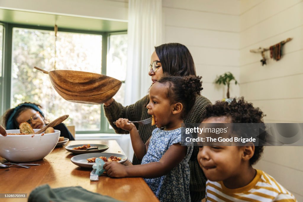 Mother passing salad bowl during family meal