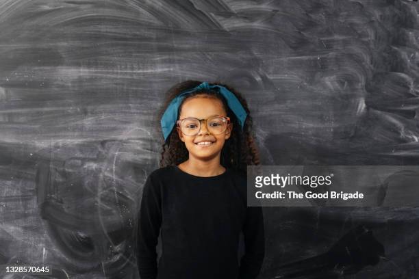 portrait of cheerful girl standing against blackboard - children board stock pictures, royalty-free photos & images