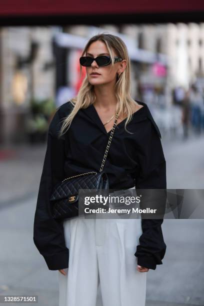 Alessa Winter wearing black Prada shades, black shirt, white pants and black Chanel leather flap bag on July 12, 2021 in Berlin, Germany.