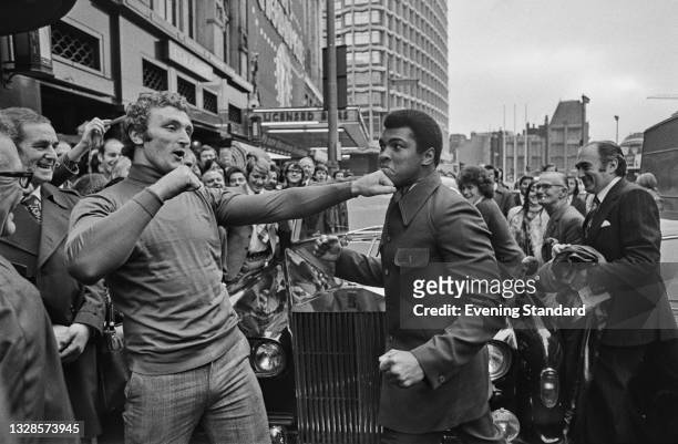 American boxer Muhammad Ali spars with British boxer Joe Bugner outside the Dominion Theatre on Tottenham Court Road in London, UK, 3rd December 1974.