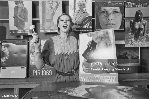 Model Nicki Howorth at an auction of the 1973 Pirelli calendar, UK, 3rd November 1974. The page she is holding is 'Breast Plate' by photographer...