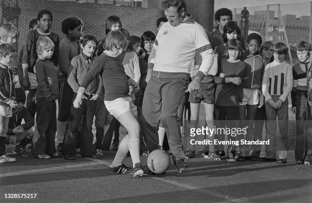 Don Revie , manager of the England national football team, playing with a group of children, UK, 31st December 1974.
