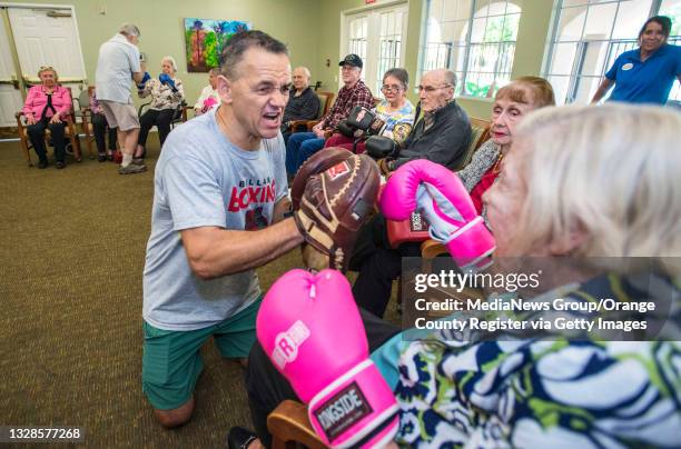 Gary Ballard, left, of Mission Viejo, a trainer and former professional boxer, growls as he tries to get Anne Carlson right, a resident at the Park...