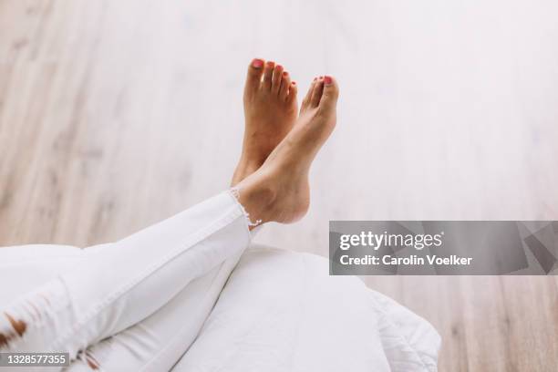 legs crossed at ankle with bare feet on a bed - white women feet fotografías e imágenes de stock