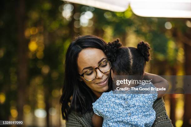 mother hugging daughter outdoors on sunny day - family hug stockfoto's en -beelden