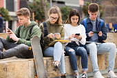 Group of teens using smartphones outdoors