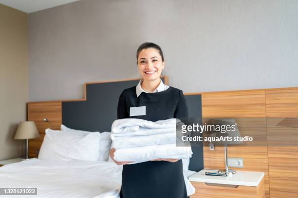 housekeeper holding stack of fresh clean towels in hotel room - employee badge stock pictures, royalty-free photos & images