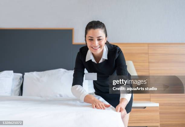 housekeeper making a bed in hotel room - hotel cleaner stock pictures, royalty-free photos & images