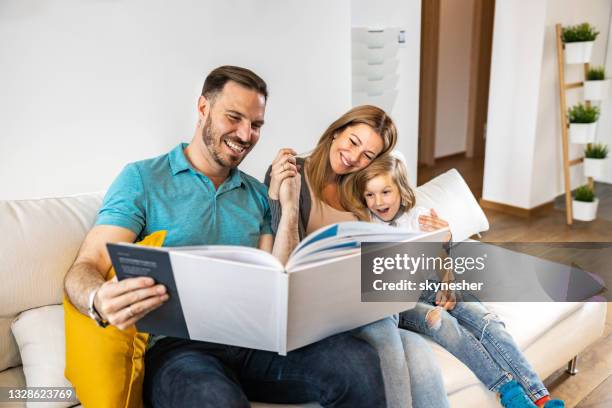 famiglia felice che guarda la rivista a casa. - catalogo foto e immagini stock