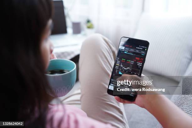 woman invest online stocks trading on mobile platform app - certificato azionario foto e immagini stock