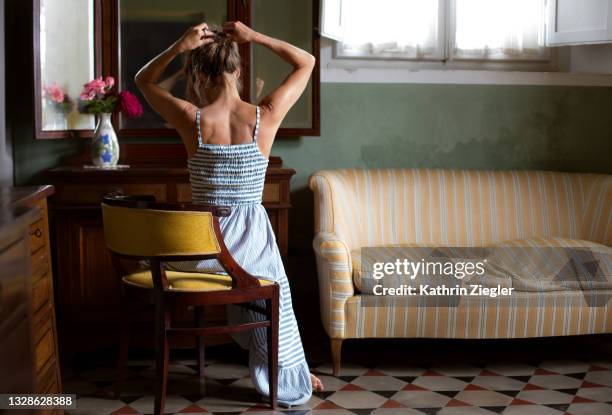 woman pinning up her hair in front of mirror, rear view - rear view mirror - fotografias e filmes do acervo