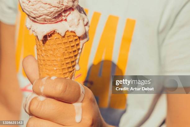 kid holding ice cream cone melting in hot summer. - kegel stock-fotos und bilder