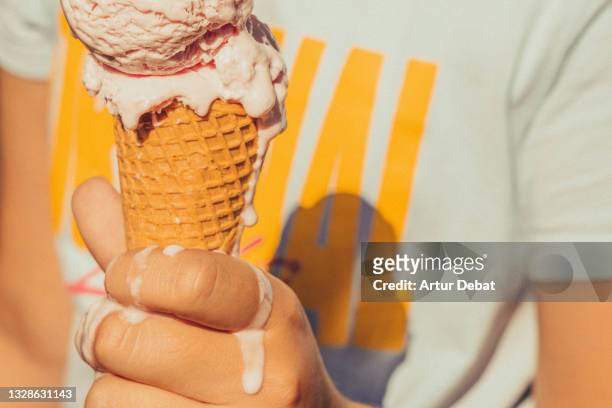 kid holding ice cream cone melting in hot summer. - calor fotografías e imágenes de stock