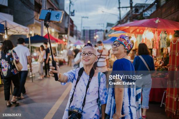 selfie time, thai senior tourists traveling at walking street night market for long weekend - stock photo - the weekend in news around the world imagens e fotografias de stock