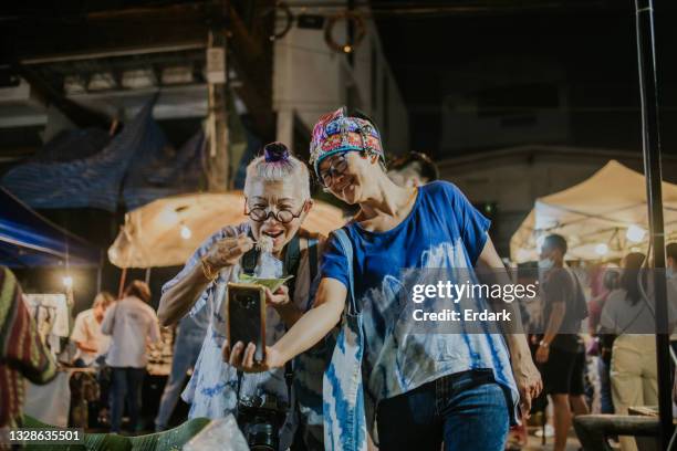 humor active senior women show her eating street local food in live streaming at night market- stock photo - the weekend in news around the world imagens e fotografias de stock