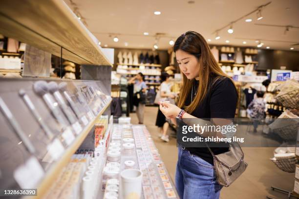 an east asian woman chooses cosmetics in a store - china east asia stock pictures, royalty-free photos & images