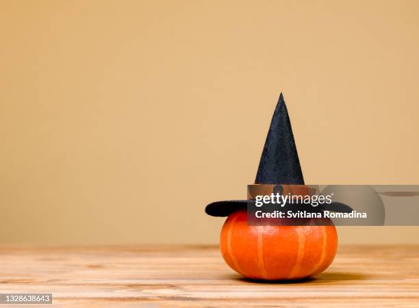 halloween composition with pumpkin and witch's hat on wooden table - halloween 2020 stock pictures, royalty-free photos & images