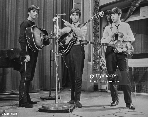 From left, John Lennon , George Harrison and Paul McCartney of English pop group The Beatles on stage during a recording session for the BBC Radio...