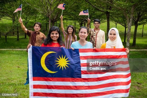 malaysians from all races proudly display their patriotic spirit and solidarity in celebrating the malaysia national day - malaysia flag stock pictures, royalty-free photos & images