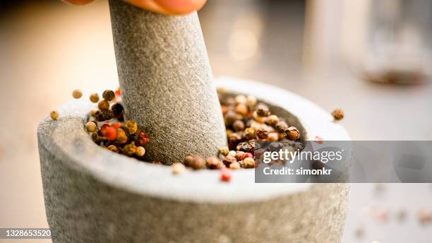 pestle crushing different types of peppers in the mortar - vijzel en stamper stockfoto's en -beelden