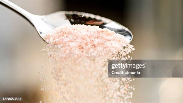 himalayan salt falling off a spoon - himalayazout stockfoto's en -beelden