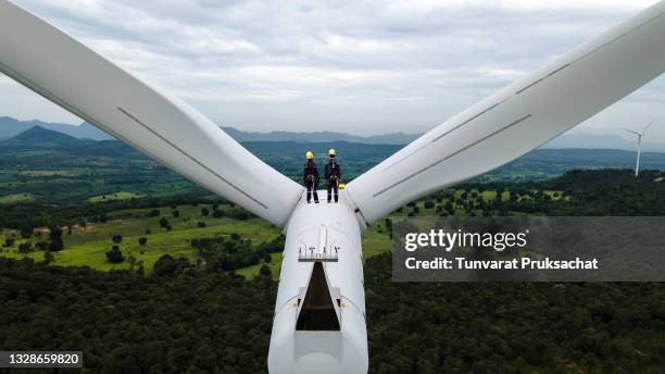 two electric engineer wearing personal protective equipment working  on top of wind turbine farm. - sustainable resources foto e immagini stock