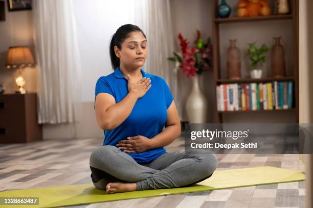 shot of a mid adult women doing yoga and arm stretching at home - hand on chest stock pictures, royalty-free photos & images