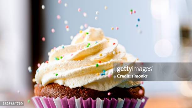 sprinkling hundreds and thousands on cupcake - confeito colorido para bolos imagens e fotografias de stock
