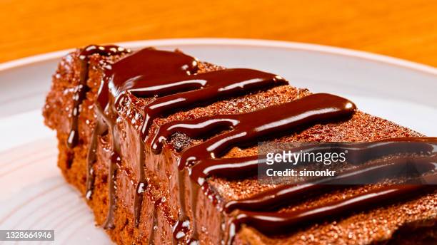 tranche de gâteau au chocolat servie à l’assiette - filet de caramel photos et images de collection