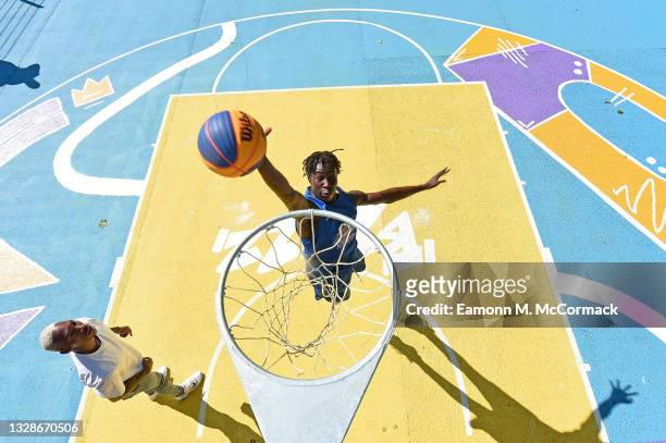 Professional Baketball player Kofi Josephs watches as a young Basketball England player attempts a dunk shot a community basketball court revamped in...