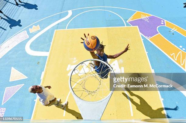 Professional Baketball player Kofi Josephs watches as a young Basketball England player attempts a dunk shot a community basketball court revamped in...