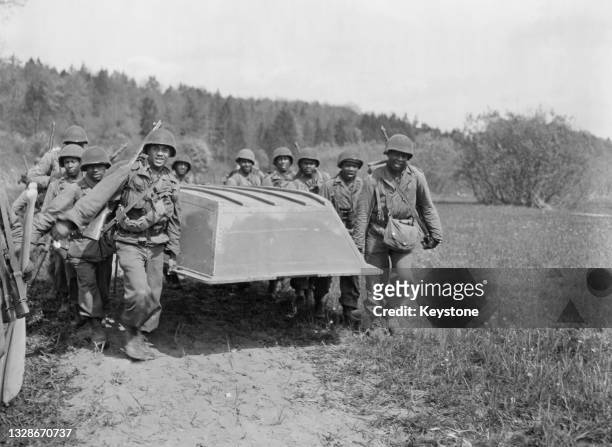 African American soldiers of the 393rd Infantry regiment, 99th Infantry Division, United States Third Army carry an assault boat prior to crossing...