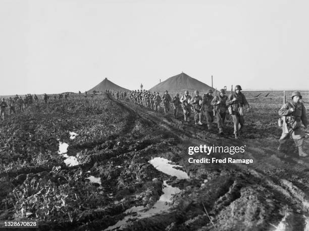 Infantrymen of the 84th Infantry Division, United States Ninth Army advance past coal slag heaps of the Ruhr Valley coal mining area in the North...