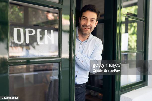 glücklicher junger restaurantbesitzer, der ein offenes schild an einer tür hängt - open sign on door stock-fotos und bilder