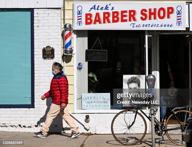 Port Washington, N.Y.: A person in a face mask walks past Alek's Barber Shop on Main Street, in Port Washington, New York on November 5, 2020.