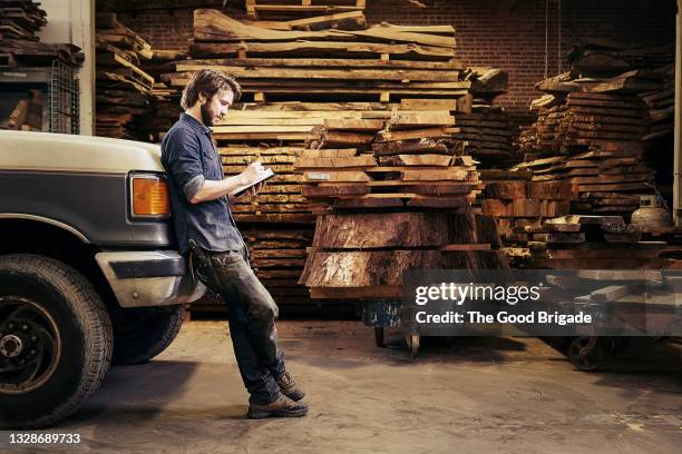 carpenter leaning on truck making notes in workshop - pick up truck stock pictures, royalty-free photos & images