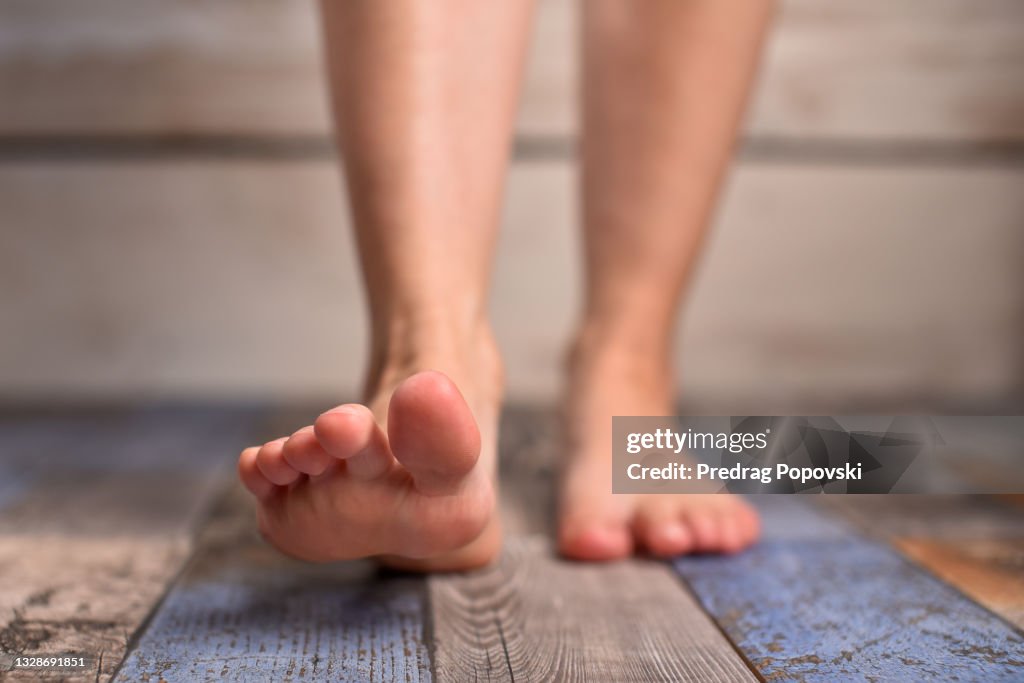 Barefoot woman with clean feet stepping on floor