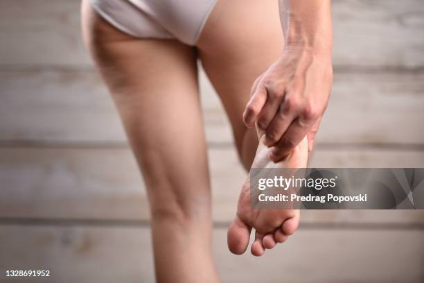 female massaging her painful feet - woman hand in pants stock pictures, royalty-free photos & images