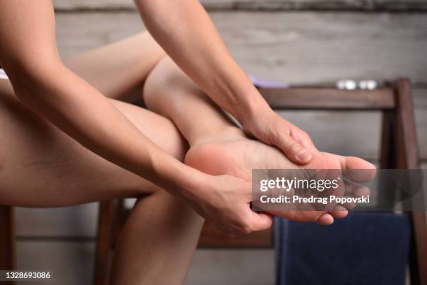 woman in pain massaging her feet - teen stockfoto's en -beelden