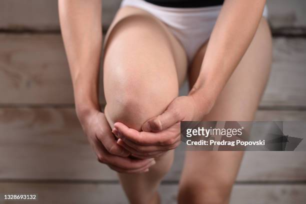 woman in pain holding her knee - gout stockfoto's en -beelden