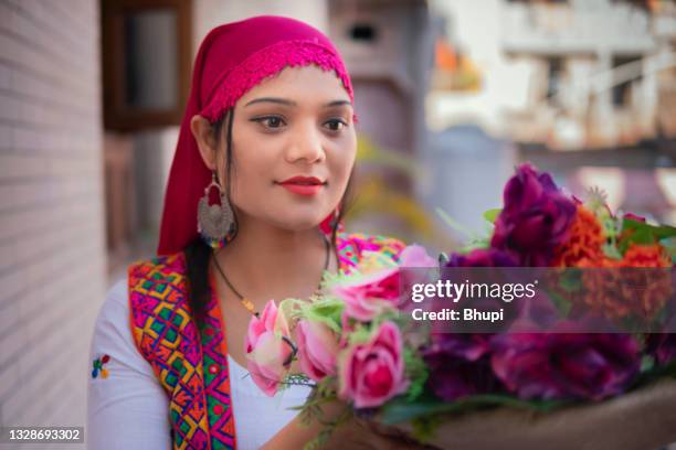 schöne glückliche traditionelle indische junge frau, die einen korb voller blumen auf dem balkon hält. - kashmir day stock-fotos und bilder