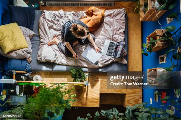 aerial view of teenage girl doing schoolwork from bedroom at home - quarantena foto e immagini stock