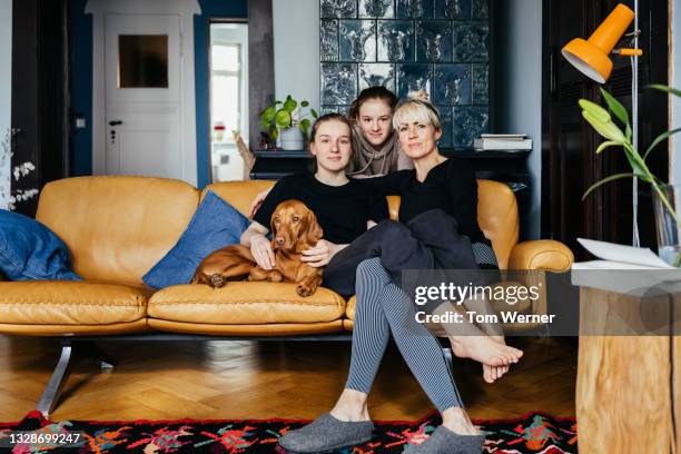 family portrait of single mom with daughters at home - girl on couch with dog foto e immagini stock