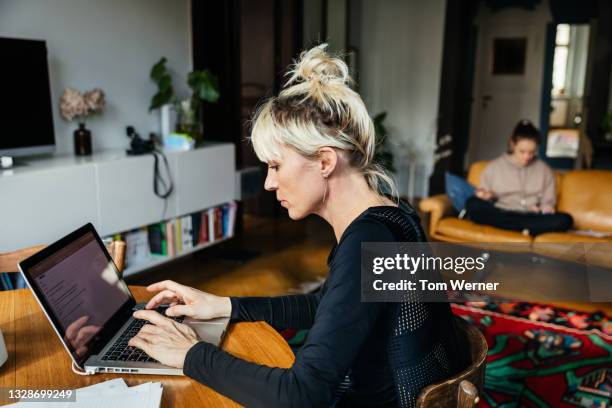 single mom typing on laptop in living room - family paperwork stock pictures, royalty-free photos & images