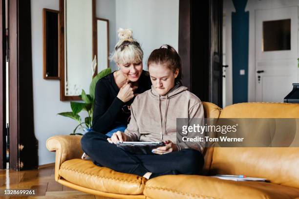 single mom helping daughter with homework in living room - moeder dochter stockfoto's en -beelden