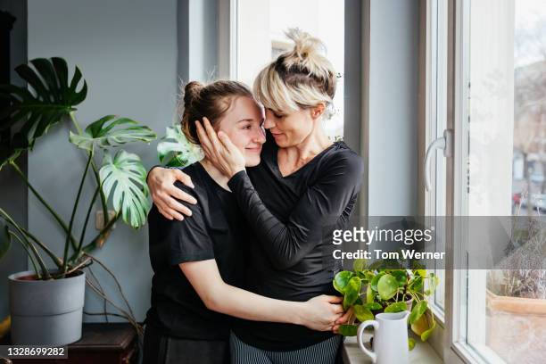 single mom affectionately hugging teenage daughter - hija fotografías e imágenes de stock